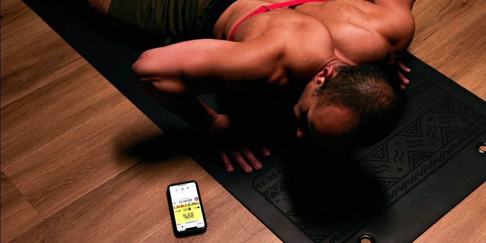 A man doing burpees, looking at his heart rate on a smartphone