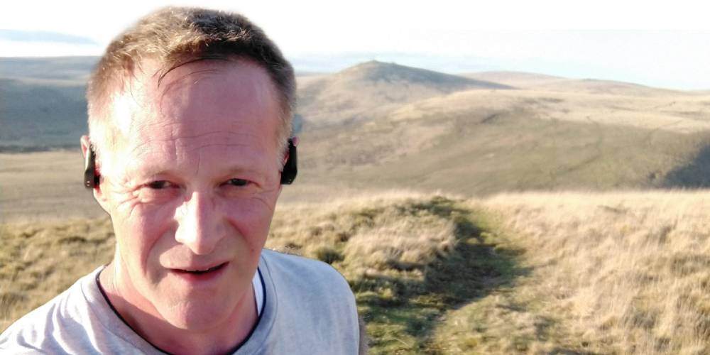 Jeremy McKnight hiking across Dartmoor National Park, with hills in the background